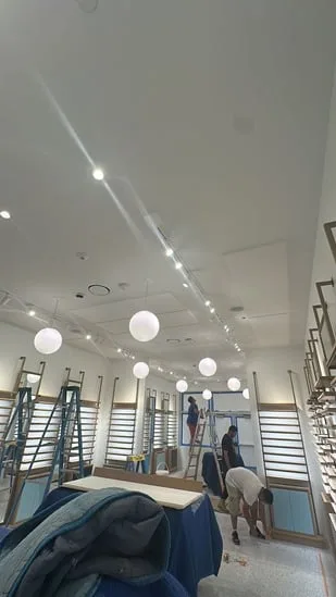 Commercial interior renovation showing workers assembling fixtures and shelving.